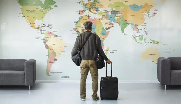 Man with luggage looking at large wall map