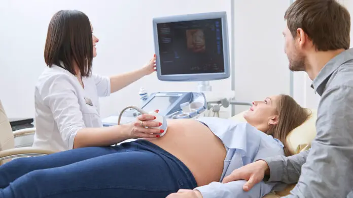 Loving couple attending doctor for pregnancy ultra sound procedu