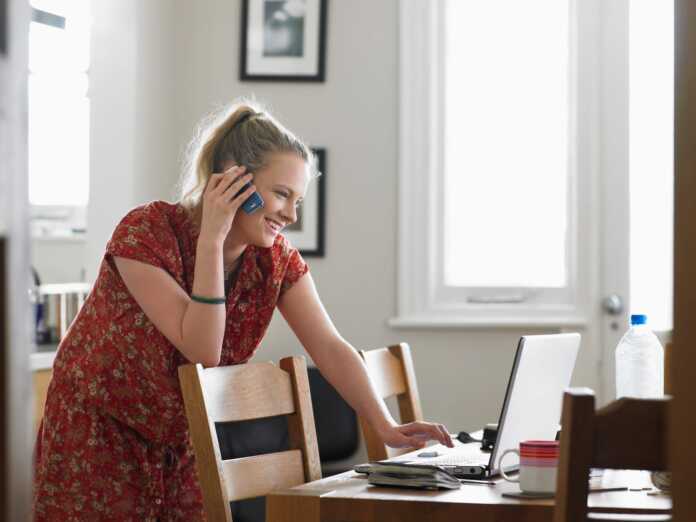 75414032_woman-on-call-using-laptop-in-dining-room